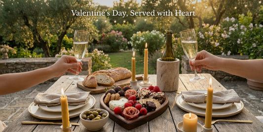 2 champagne flutes raised to toast, on an outdoor meal setting with charcuterie and candles