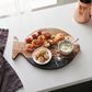Black marble and acacia wood fish-shaped serving board, 11.75 x 7.75 inches, with a black marble accent for serving cheese, charcuterie, appetizers, and snacks.