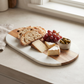 White marble and acacia wood oval serving board, 13-inch by 7-inch, for charcuterie and entertaining.