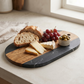 Black marble and acacia wood oval serving board, 13-inch by 7-inch, for charcuterie and entertaining.