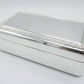 A shiny rectangular silver jewelry box with a beaded edge design on its lift-top lid.