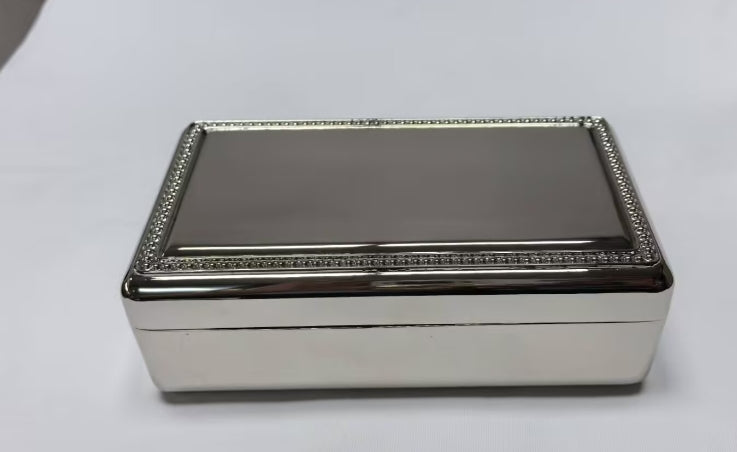 A shiny silver Rectangular Beaded Edge Lift-Top Jewelry Box with a smooth, reflective surface and beaded trim.