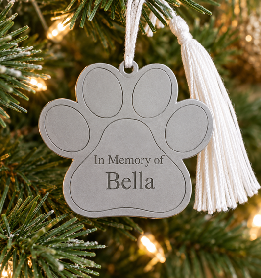 Dog paw ornament with white tassel, 2.5 x 3.4 inches, personalized holiday keepsake in a white box.