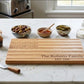 Engraved American Flag-shaped acacia wood serving board in a natural brown finish, designed for charcuterie, cheese, fruit, or appetizers, and suitable for personalization as a unique gift.